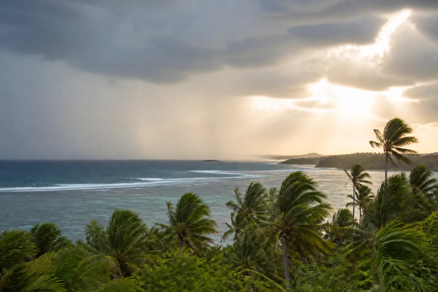 Sun and a rain curtain sharing the sky above Siargao's coast