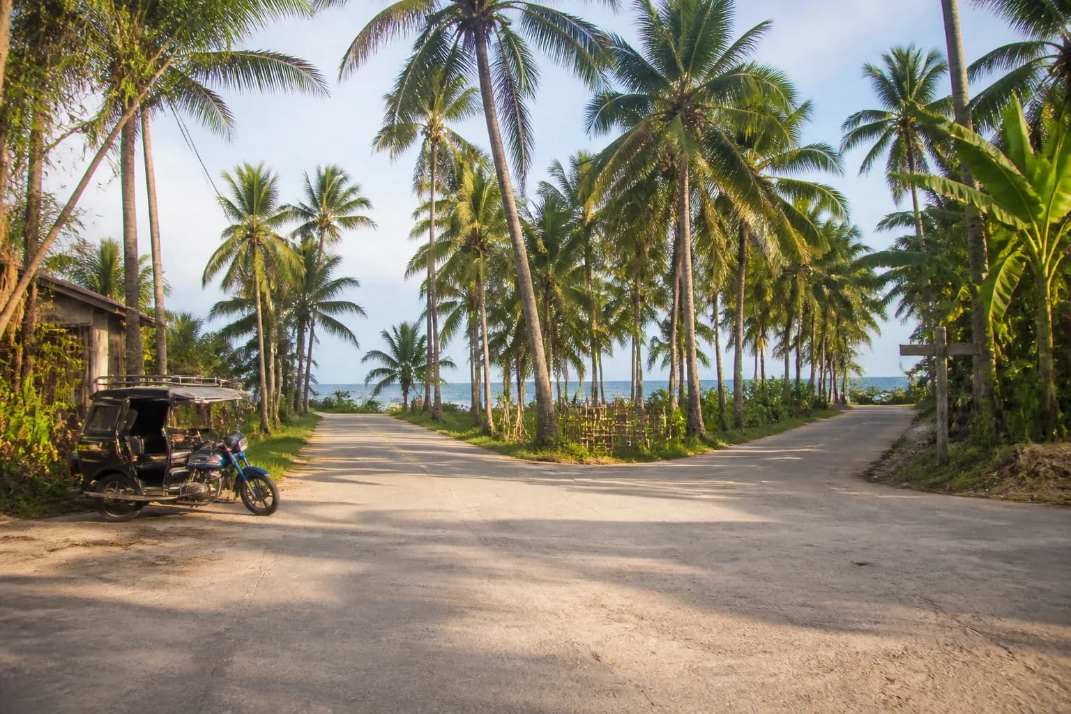 A quiet Siargao road junction with a local tricycle